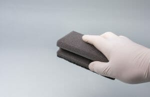 a hand with globes holding a wash sponge