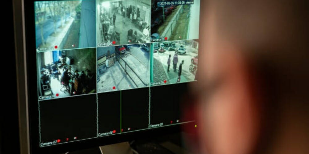 a blurry head of a man viewing cctv footages on pc