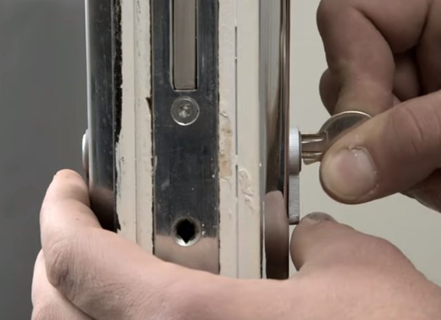 man inserting the key to the keyhole of the doorknob